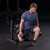 Man exercising on a bulgarian split squat stand with dumbbells in a gym setting