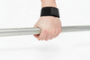 Hand wearing a black wrist support holding a barbell on a white background