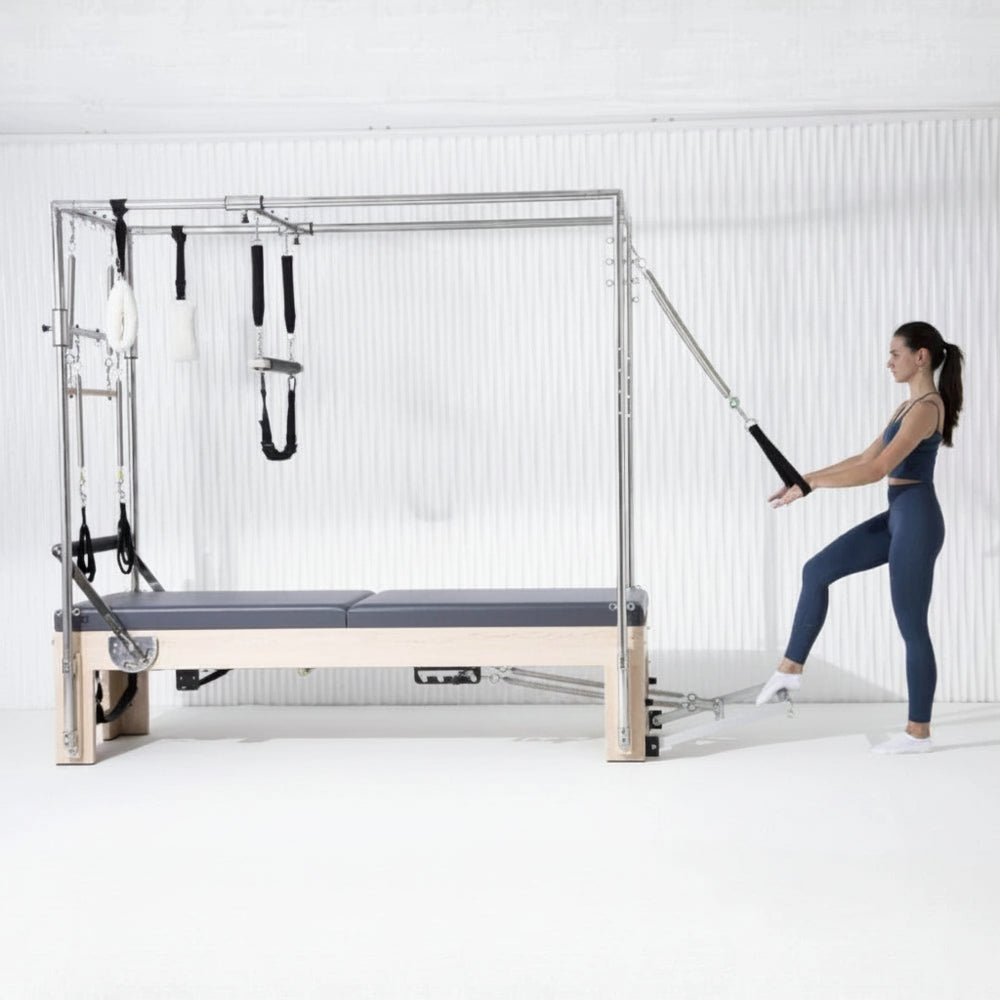 Woman exercising on a Pilates reformer machine in a white room