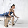 Woman using a Pilates reformer machine in a studio setting