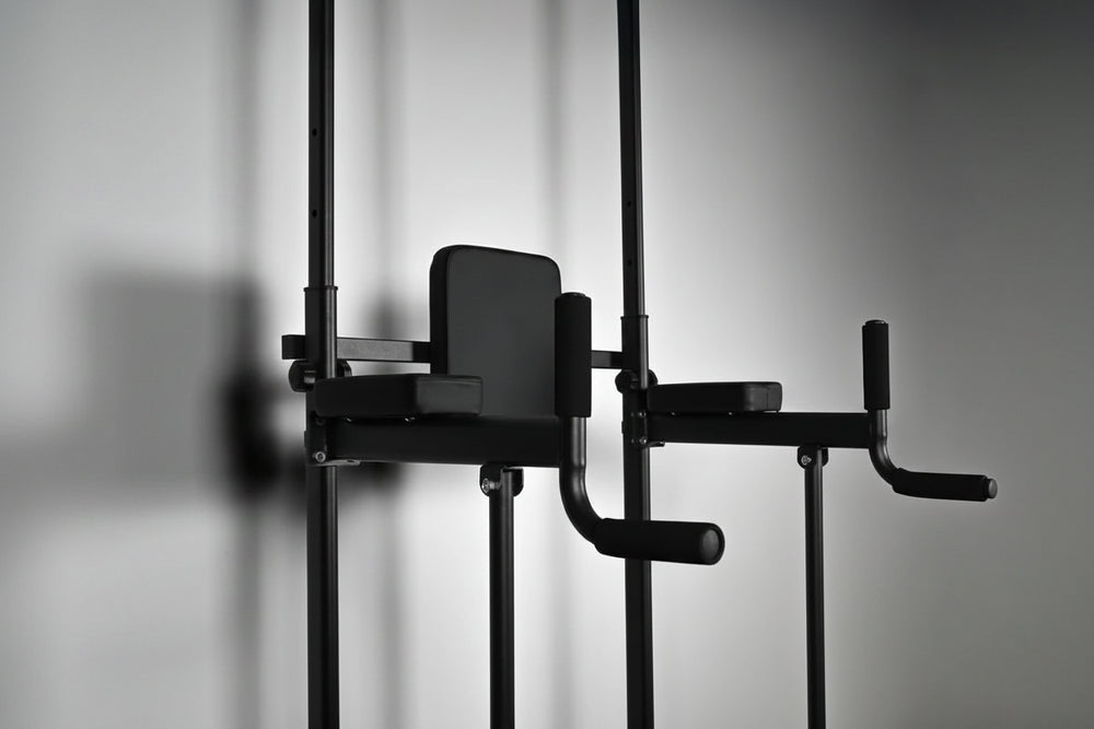 Black pull-up dip machine against a gray background
