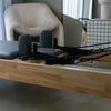 Oak Pilates reformer machine with dark padding in a home gym