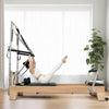 Woman using a pilates reformer tower machine in a home gym setting