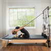 Woman using a pilates reformer in a home gym setting