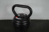 Black adjustable kettlebell on a textured floor