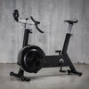 Black exercise bike against a gray concrete wall.