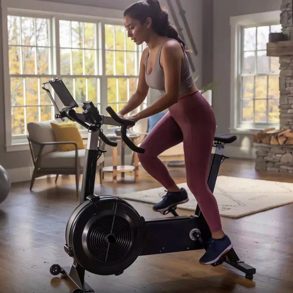 Woman using an air resistance bike in a home gym setting