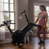 Woman moving an exercise bike in a home gym setting