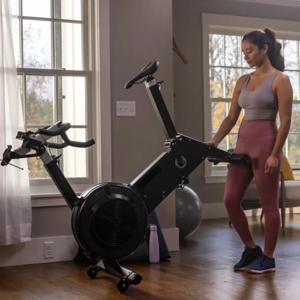 Woman moving an exercise bike in a home gym setting