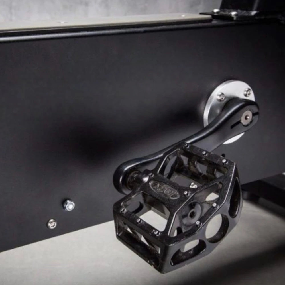 Close-up of a black pedal mechanism on an exercise bike on a dark background