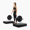 Woman dropping barbell onto drop pads on a white background