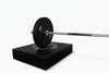 Barbell with weight plate on a black drop pad against a white background