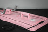 Pink exercise board with handles and resistance band on a black surface