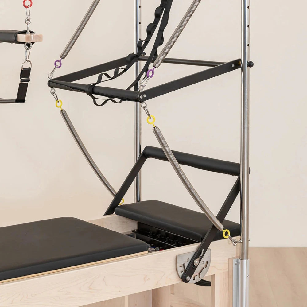 Pilates reformer machine with attachments on a beige background