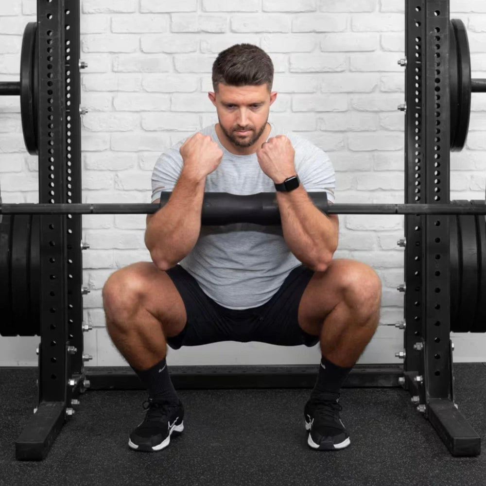 Man using a squat pad on a barbell in a gym setting