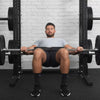 Man using squat pad on barbell rested on his lap in a gym setting