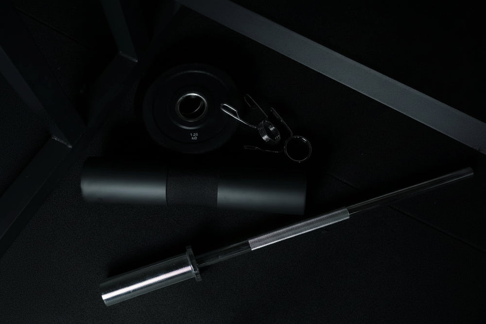 Gym equipment including a barbell and weights on a dark surface