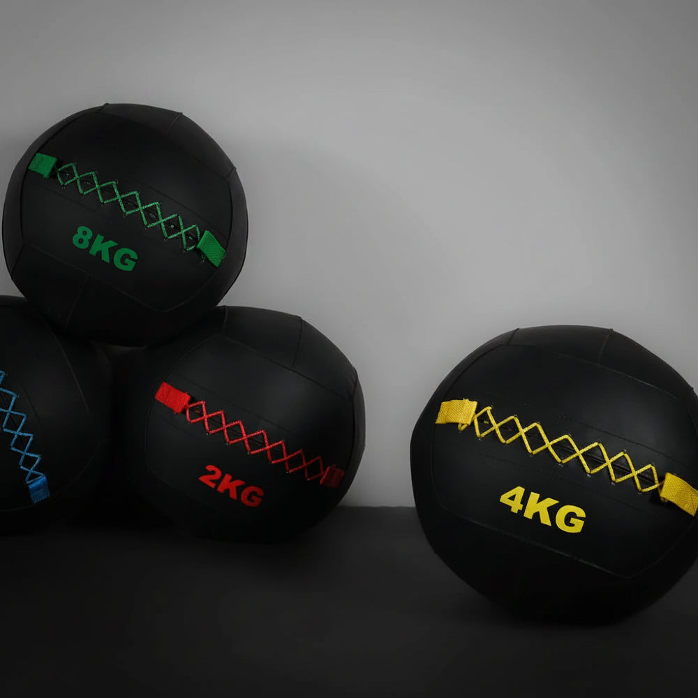 Four wall balls at different weights against a dark background