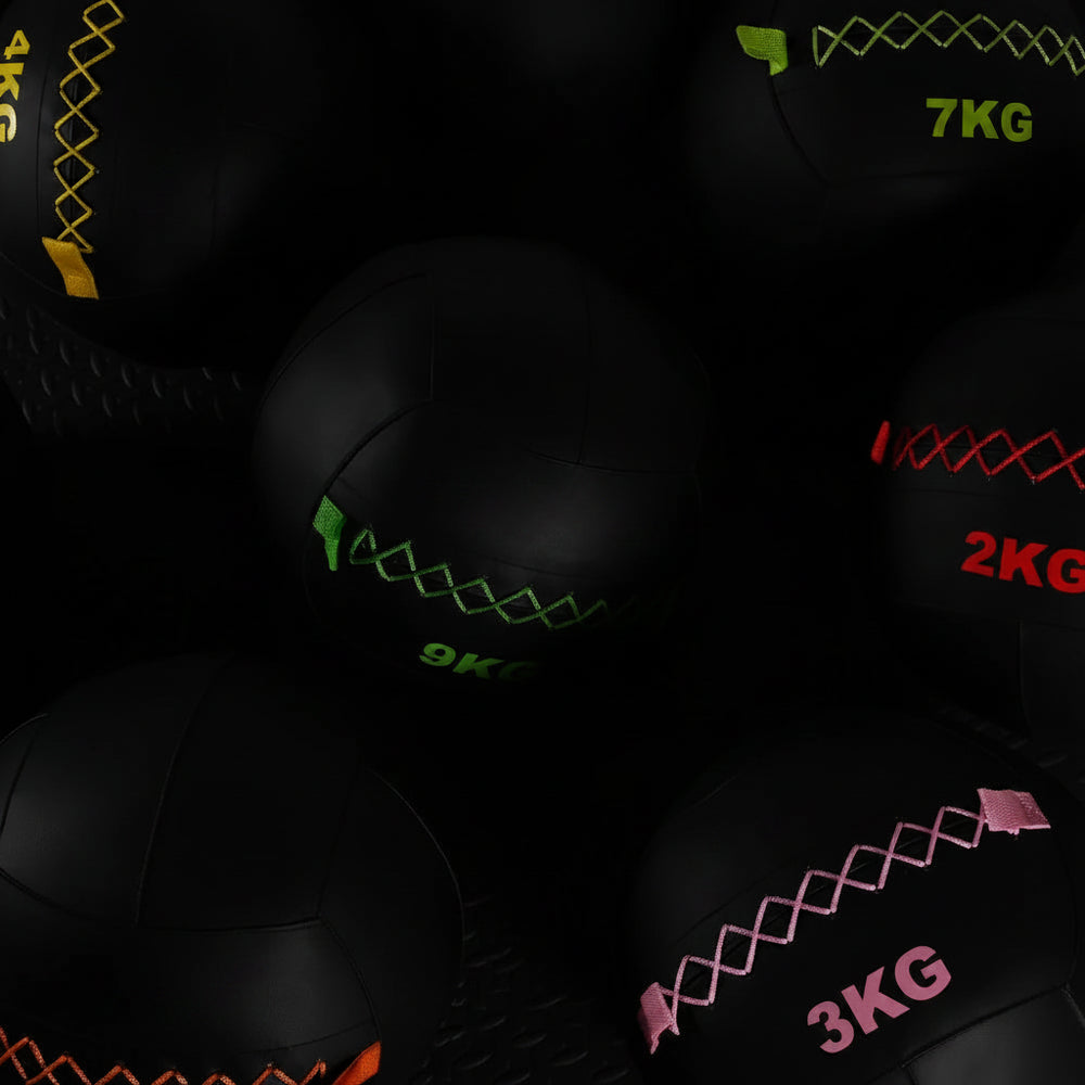 Black wall balls with weight markings on a dark background