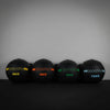 Four black slam balls with colour coded weights against a grey wall