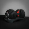 Pair of adjustable dumbbells on a stand with a dark background