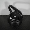 Black adjustable dumbbell on a textured surface with a neutral background