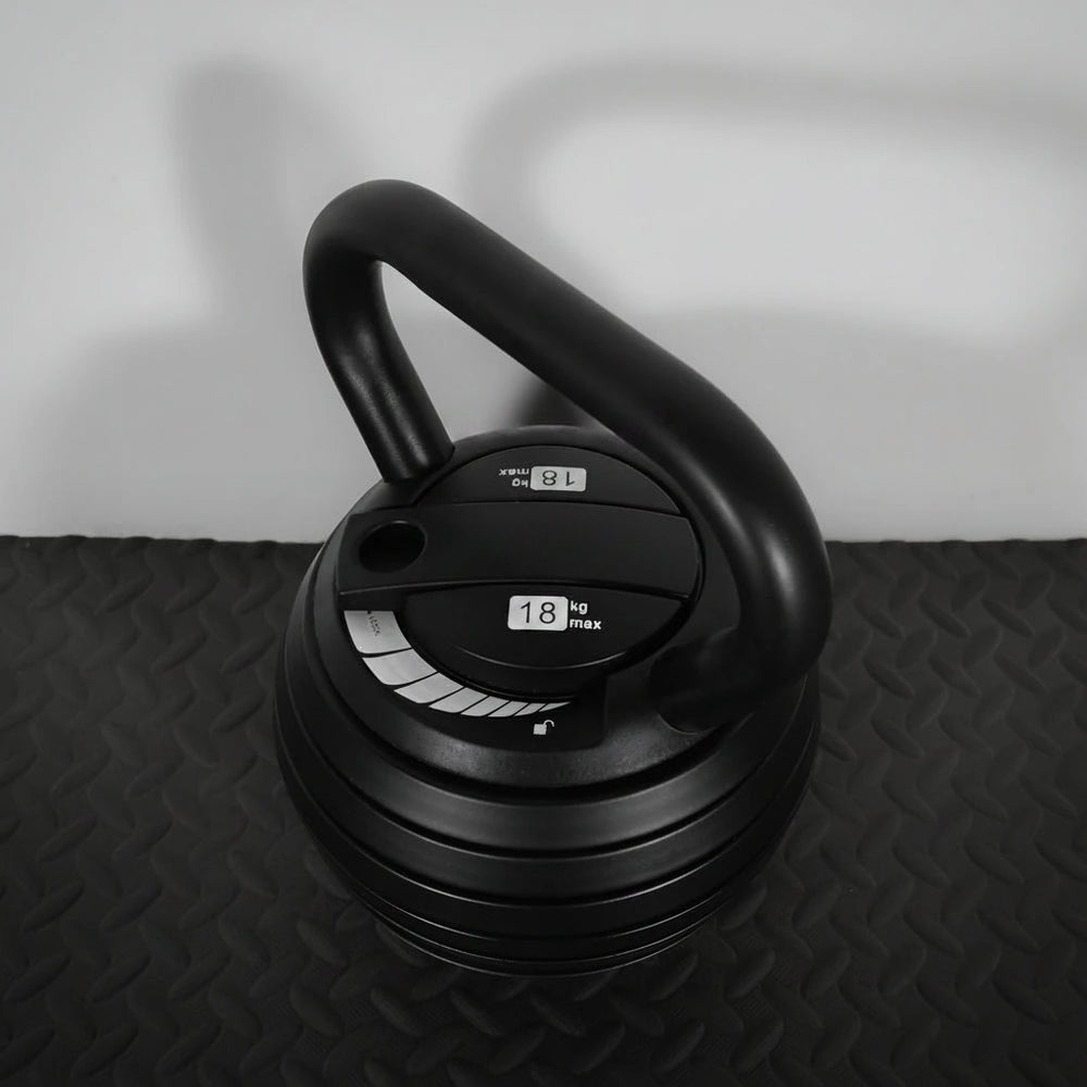 Black adjustable dumbbell on a textured surface with a neutral background