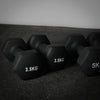 Black neoprene dumbbells of various weights on a dark floor