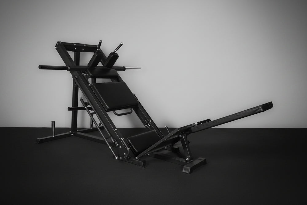 Black gym leg press and hack squat machine against a gray wall