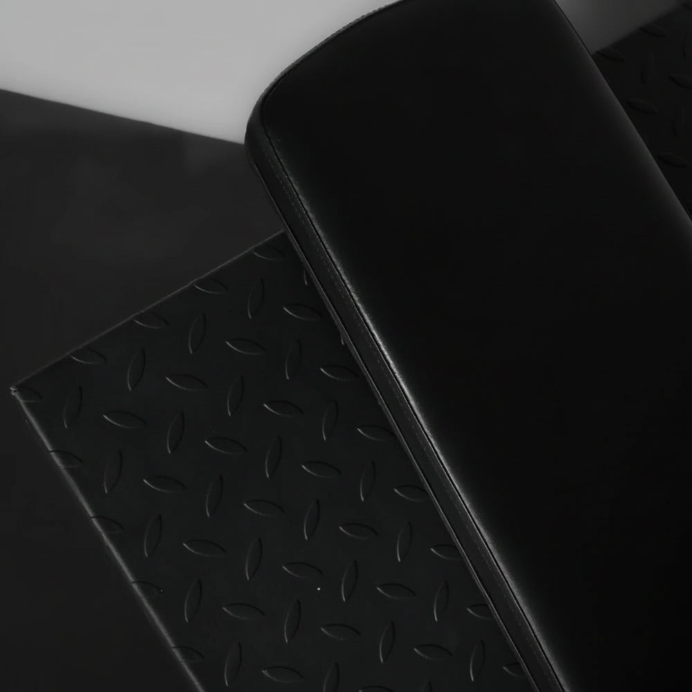 Black cushioned back rest of a leg press and hack squat machine on a dark background
