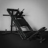 Commercial leg press and hack squat gym machine on a dark background