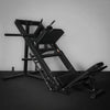 Black leg press machine against a gray wall