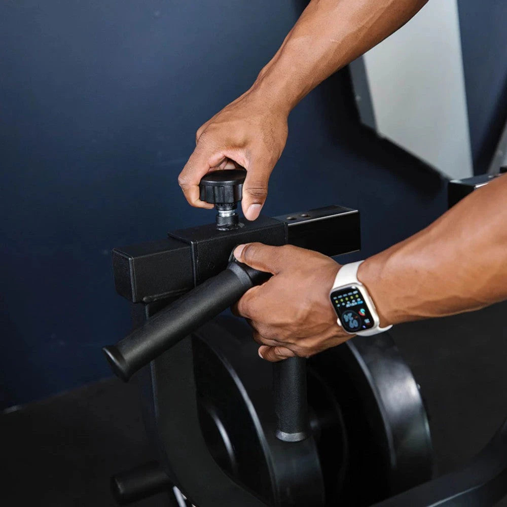 Person using a rowing machine with a focus on hands and equipment.