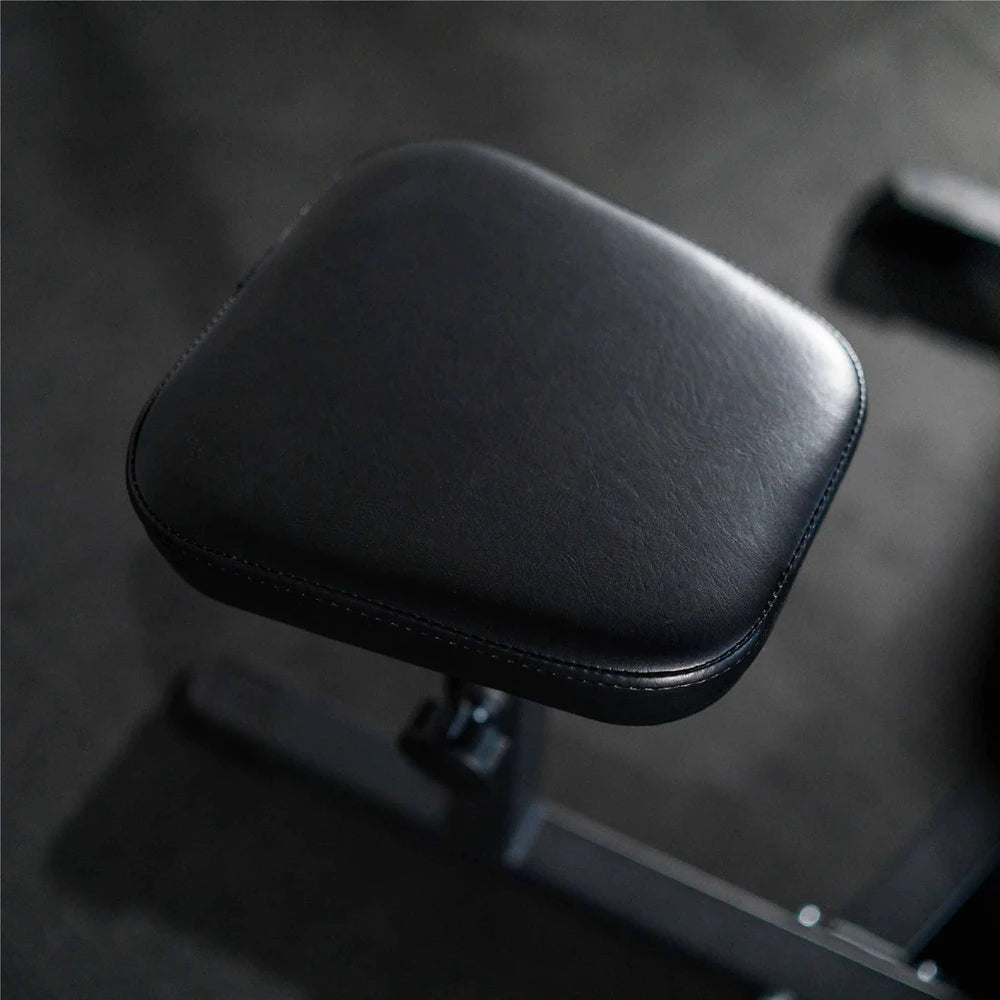 Black leather seat cover on a gym machine with a dark background