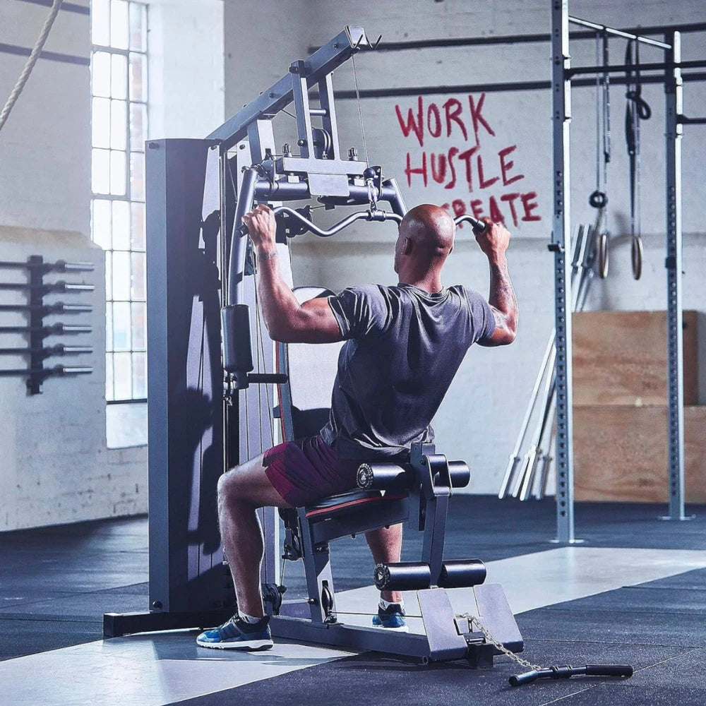 Man exercising on a gym machine with motivational text on the wall.