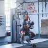 Man exercising with dumbbells on a machine in a gym with motivational quote on wall