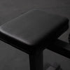Black cushioned calf raise machine seat on a dark background