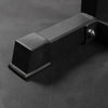Black metal sturdy foot of a calf raise machine on a dark gray background