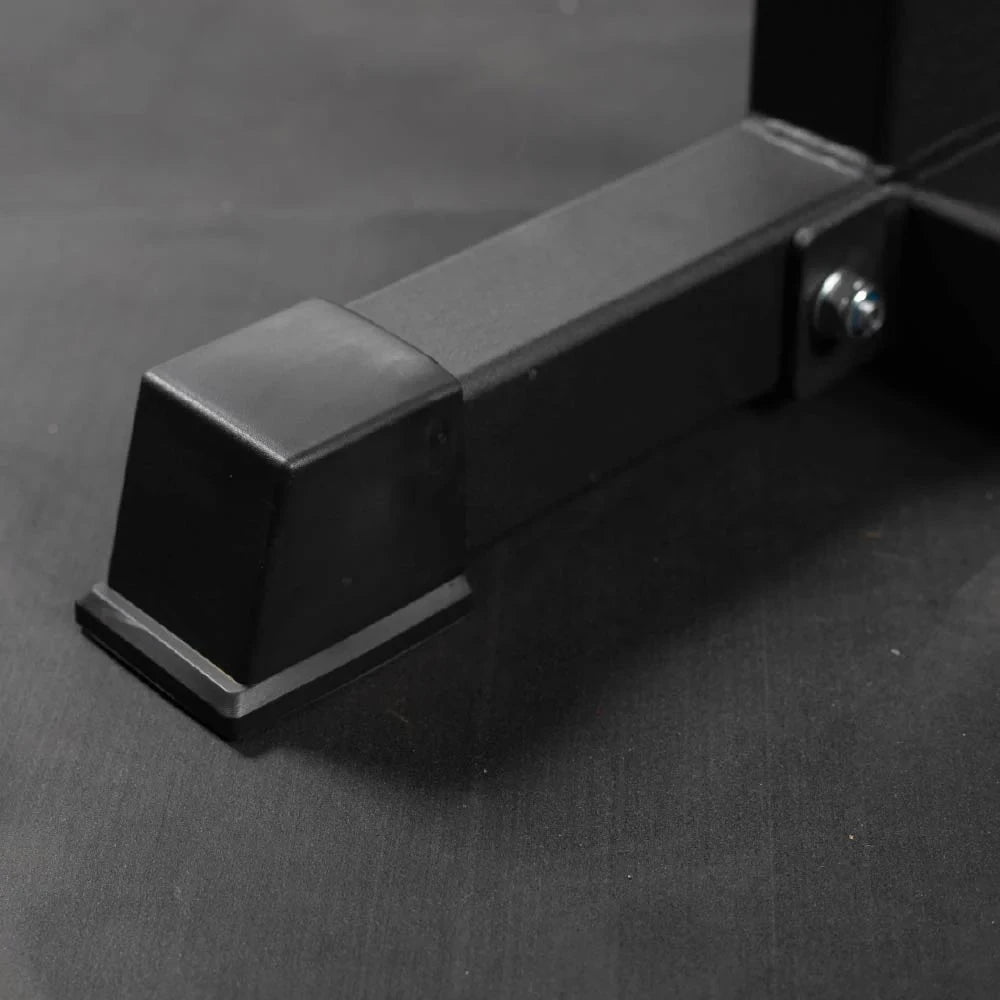 Black metal sturdy foot of a calf raise machine on a dark gray background