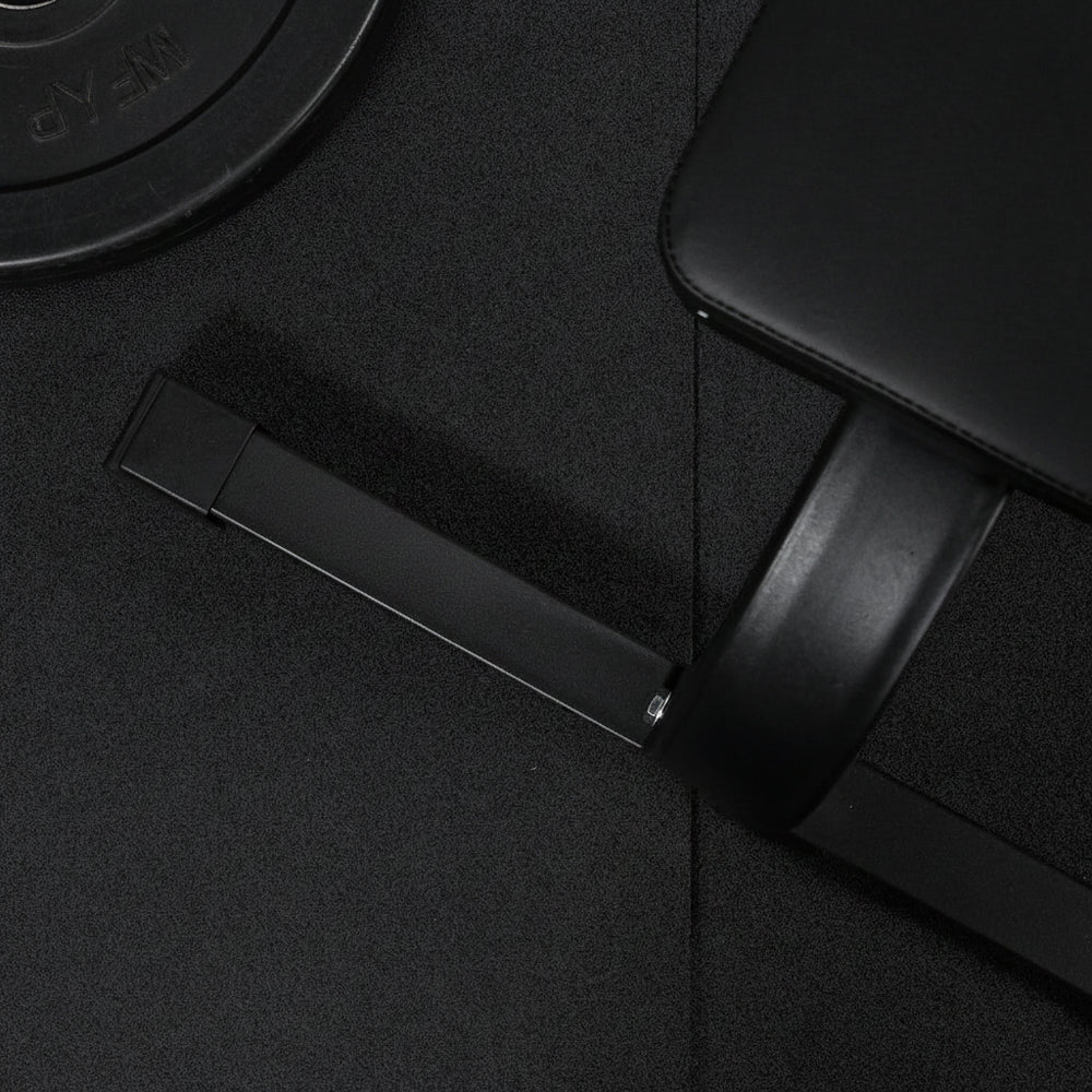 Close up of legs of a preacher curl bench and weight on a gym floor