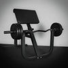 Black weight bench with weights on a dark floor against a light wall