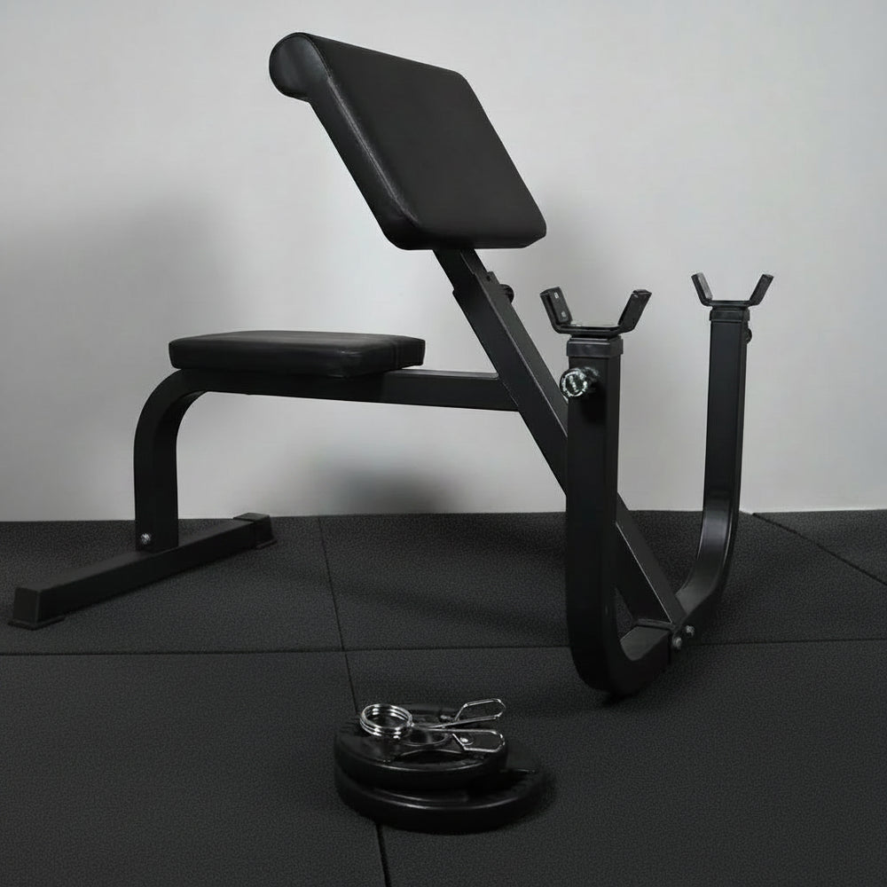 Black weight bench with weights and barbell on a dark floor.