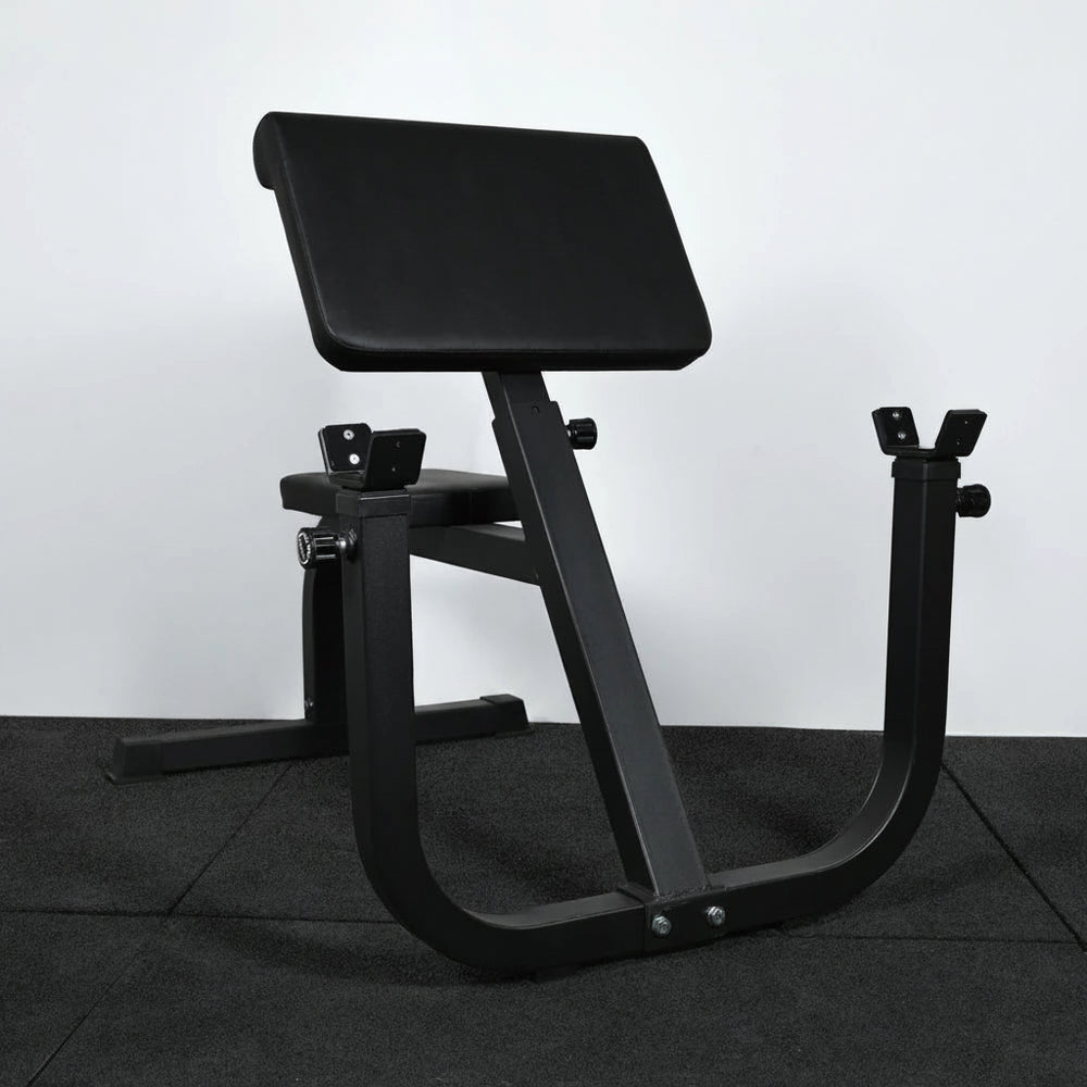 Angled view of preacher curl bench on a black tiled floor