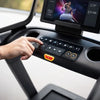 Person pushing buttons on control panel of a treadmill