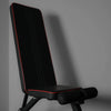 Black gym bench with red piping in upright position