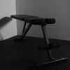 Gym bench in flat position on black textured floor and grey walls