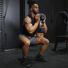 Man performing a squat with dumbbells in a gym setting