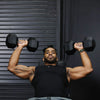 Man performing a bench press with dumbbells against a dark background
