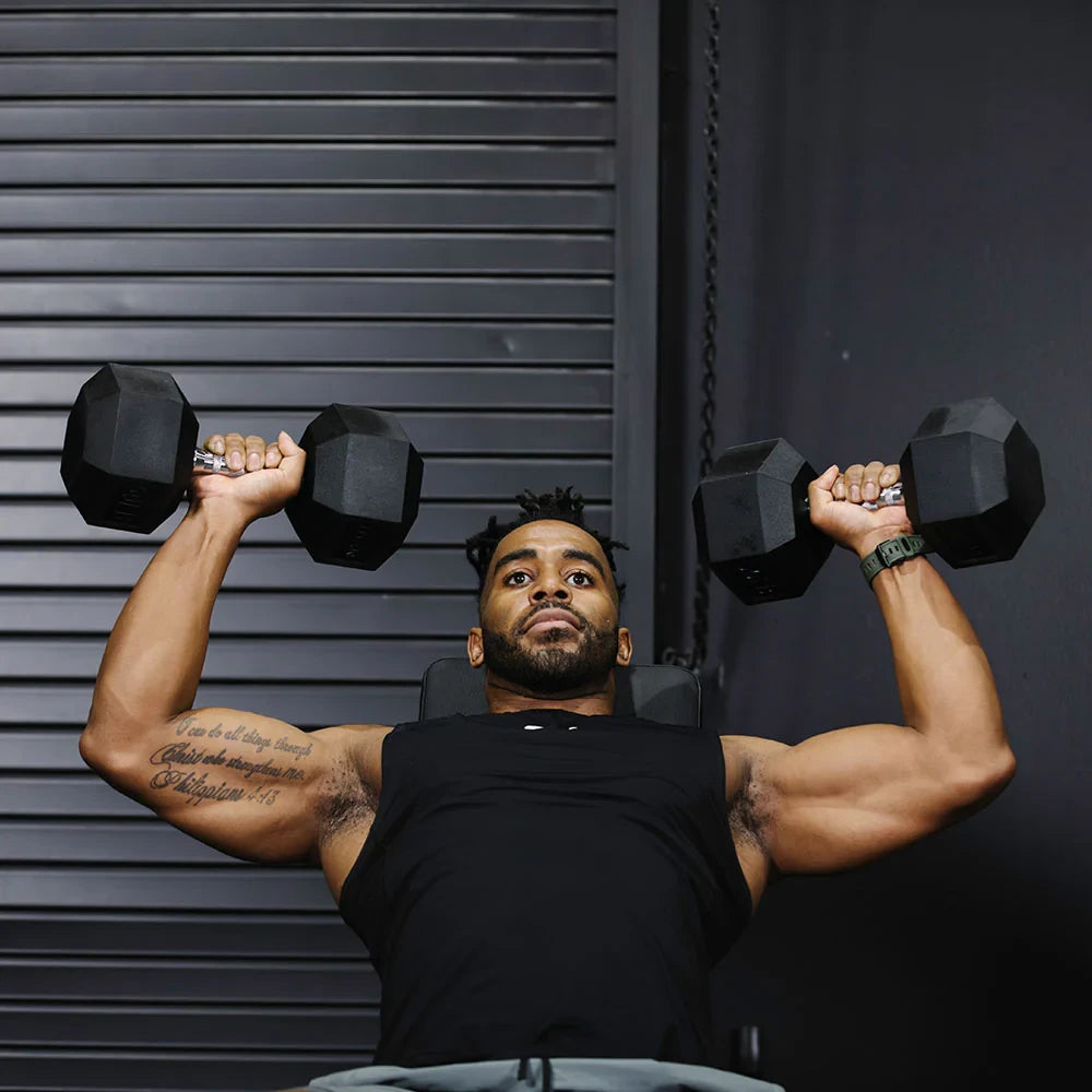 Man performing a bench press with dumbbells against a dark background