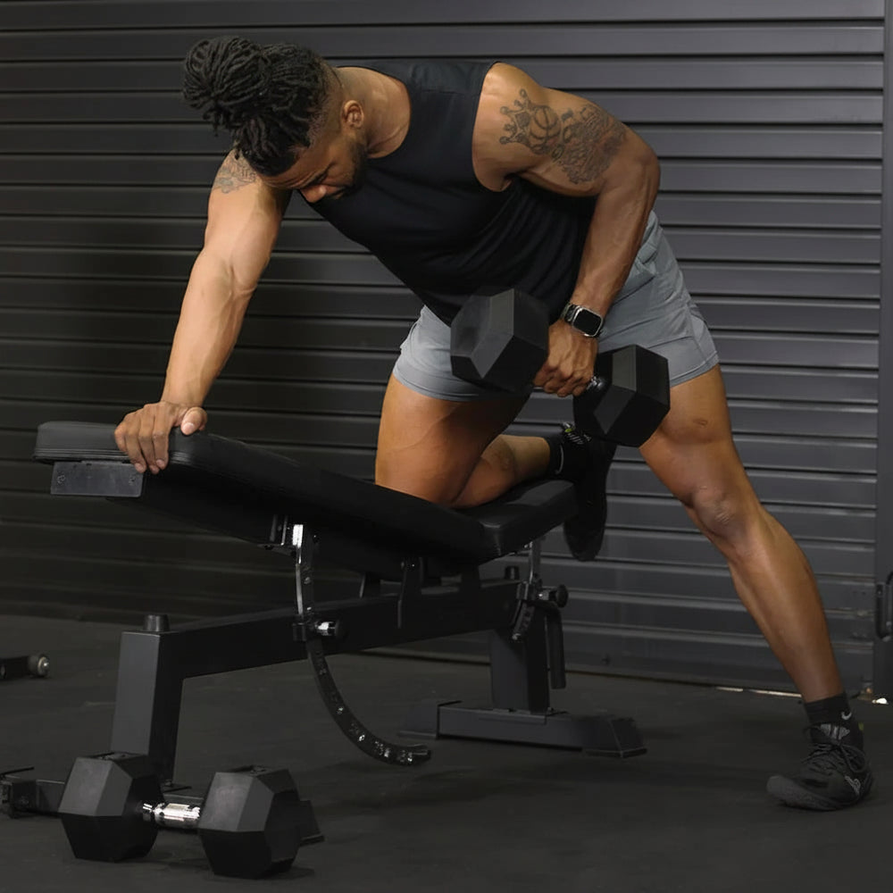 Man working out in a home gym setting with dumbbell and a workbench